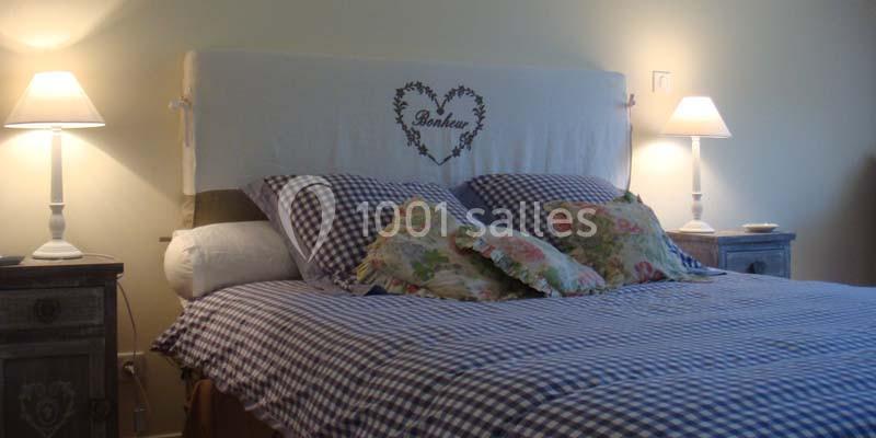 Lit double avec tête de lit ornée d'un cœur et du mot ’Bonheur’, entouré de lampes de chevet allumées.