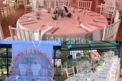 Salle à manger avec table dressée, chaises transparentes, poutre apparente, canapé bleu et tableaux au mur.