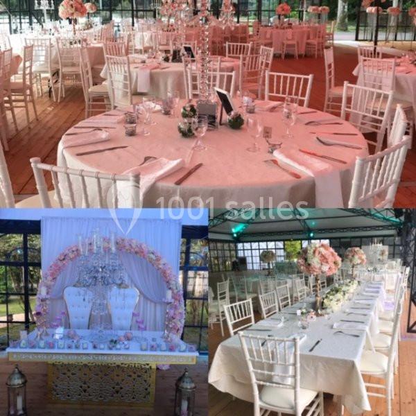 Salle décorée pour un événement avec tables rondes et rectangulaires ornées de nappes blanches et arrangements floraux.