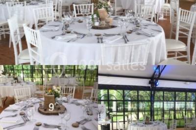 Salle à manger avec table dressée, chaises transparentes, poutre apparente, canapé bleu et tableaux au mur.