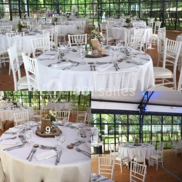 Salle de réception lumineuse avec tables rondes dressées, nappes blanches et chaises blanches, vue sur un jardin.