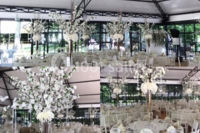 Salle à manger avec table dressée, chaises transparentes, poutre apparente, canapé bleu et tableaux au mur.