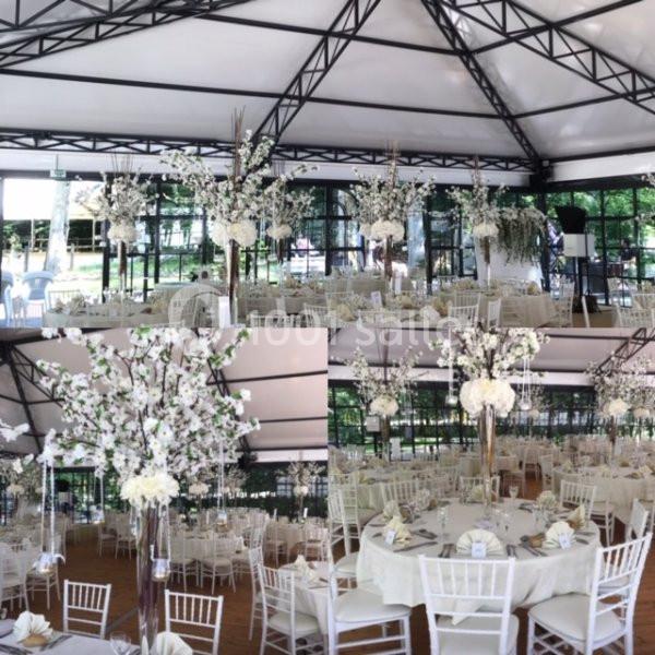 Salle de réception décorée avec des tables rondes, nappes blanches, chaises assorties et arrangements floraux élégants.