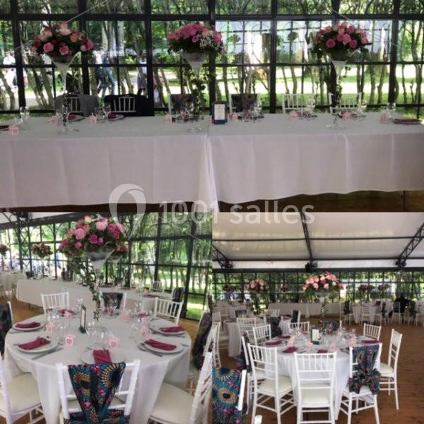 Tables décorées pour un événement, avec nappes blanches, chaises blanches et compositions florales roses dans une salle…