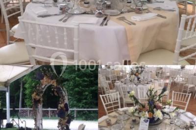 Salle à manger avec table dressée, chaises transparentes, poutre apparente, canapé bleu et tableaux au mur.