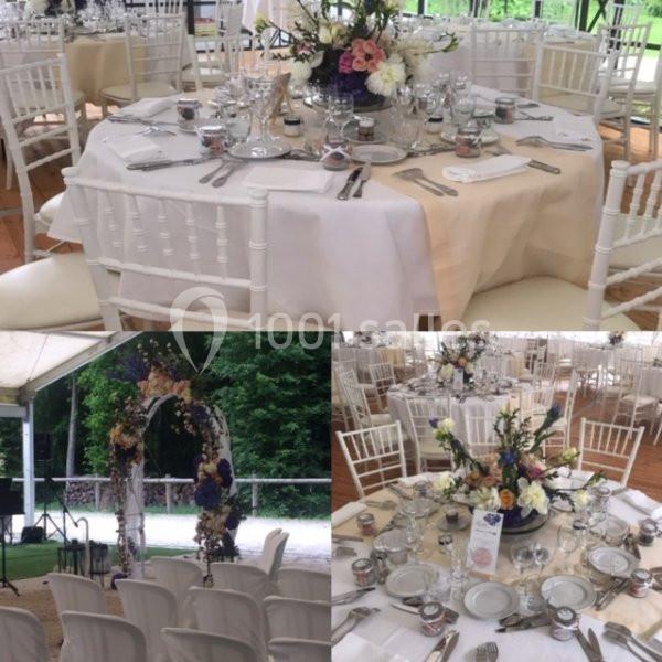 Tables élégamment dressées pour un événement, avec des fleurs en centre de table et une arche florale en arrière-plan.