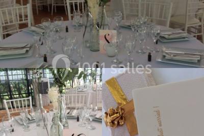 Salle à manger avec table dressée, chaises transparentes, poutre apparente, canapé bleu et tableaux au mur.