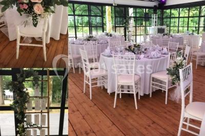 Salle à manger avec table dressée, chaises transparentes, poutre apparente, canapé bleu et tableaux au mur.