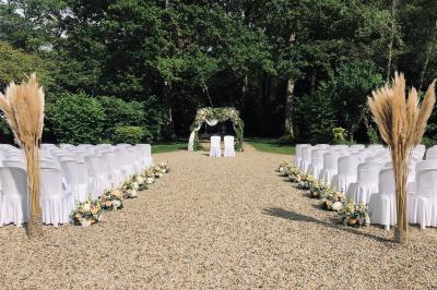 Salle à manger avec table dressée, chaises transparentes, poutre apparente, canapé bleu et tableaux au mur.