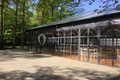 Salle à manger avec table dressée, chaises transparentes, poutre apparente, canapé bleu et tableaux au mur.