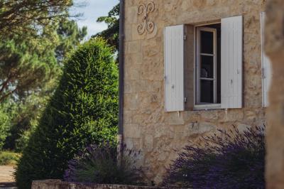 Façade en pierre d'un bâtiment ancien avec une fenêtre à barreaux et un toit en bois sous un ciel bleu.