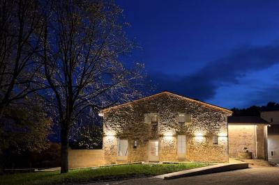 Façade en pierre d'un bâtiment ancien avec une fenêtre à barreaux et un toit en bois sous un ciel bleu.