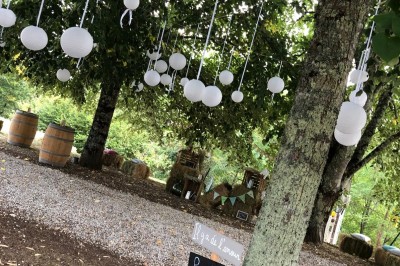 Salle de réception rustique avec murs en pierre, poutres apparentes, décorations florales et lumière naturelle.