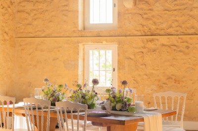 Bouteille de vin rosé posée sur une table décorée de fleurs, entourée de verres et d'assiettes.