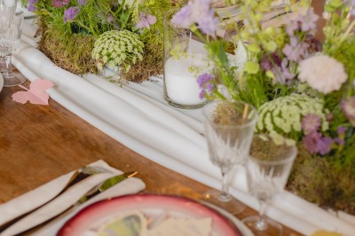Bouteille de vin rosé posée sur une table décorée de fleurs, entourée de verres et d'assiettes.
