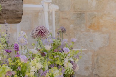 Bouteille de vin rosé posée sur une table décorée de fleurs, entourée de verres et d'assiettes.
