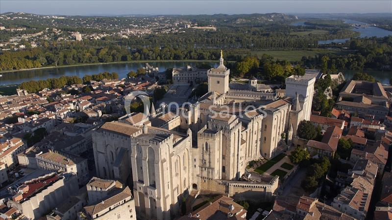 Vue aérienne du Palais des Papes à Avignon, entouré de bâtiments historiques et bordé par le Rhône.