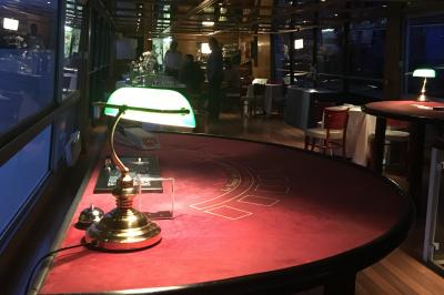 Salle de restaurant sur un bateau avec tables rondes dressées, nappes blanches et vue sur un paysage fluvial.