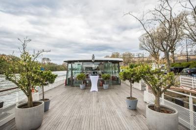 Salle de restaurant sur un bateau avec tables rondes dressées, nappes blanches et vue sur un paysage fluvial.