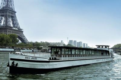 Salle de restaurant sur un bateau avec tables rondes dressées, nappes blanches et vue sur un paysage fluvial.