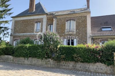 Lit double avec draps blancs dans une chambre mansardée, parquet au sol et poutres apparentes.