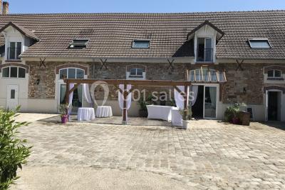 Lit double avec draps blancs dans une chambre mansardée, parquet au sol et poutres apparentes.