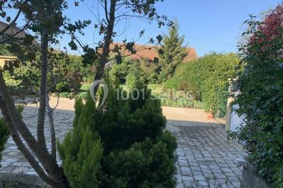 Lit double avec draps blancs dans une chambre mansardée, parquet au sol et poutres apparentes.