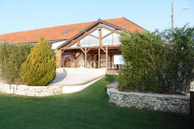 Lit double avec draps blancs dans une chambre mansardée, parquet au sol et poutres apparentes.