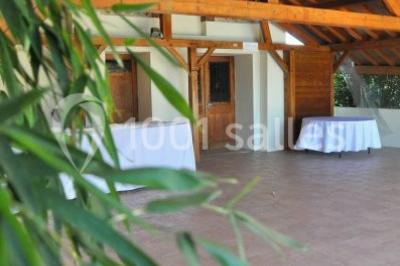 Lit double avec draps blancs dans une chambre mansardée, parquet au sol et poutres apparentes.