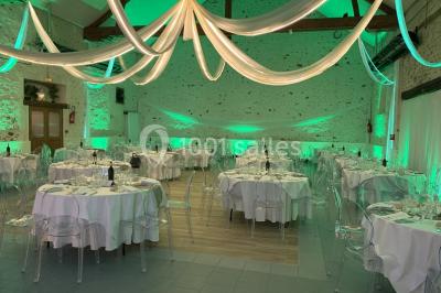 Lit double avec draps blancs dans une chambre mansardée, parquet au sol et poutres apparentes.