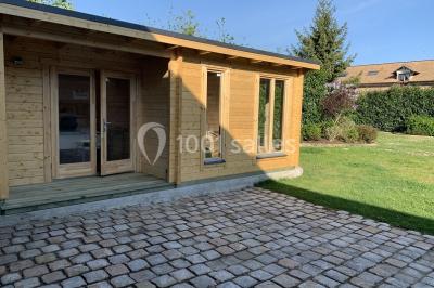 Lit double avec draps blancs dans une chambre mansardée, parquet au sol et poutres apparentes.