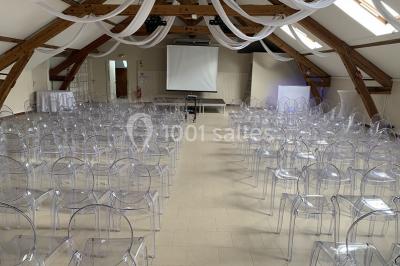 Lit double avec draps blancs dans une chambre mansardée, parquet au sol et poutres apparentes.