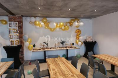 Structure gonflable colorée en forme d'arche, installée sur une cour pavée devant des maisons en briques.