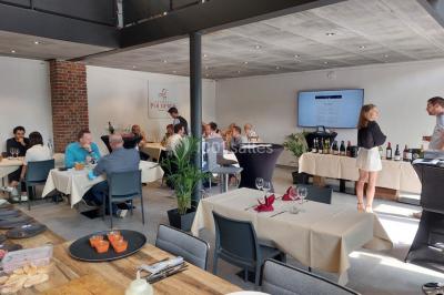 Salle de réunion moderne avec chaises disposées en rangées, tables hautes et grandes baies vitrées laissant entrer la…