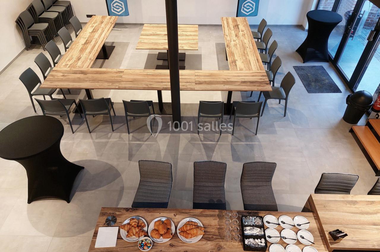 Salle de réunion aménagée en U avec des chaises, tables en bois, et buffet de viennoiseries au premier plan.
