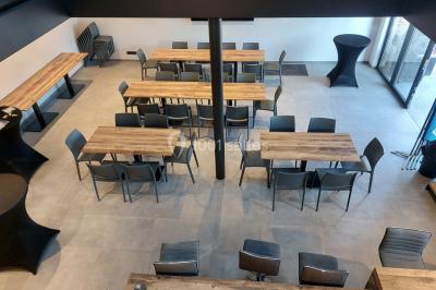 Salle de réunion moderne avec chaises disposées en rangées, tables hautes et grandes baies vitrées laissant entrer la…