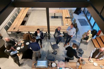 Salle de réunion moderne avec chaises disposées en rangées, tables hautes et grandes baies vitrées laissant entrer la…