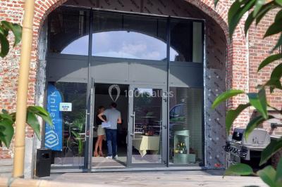 Salle de réunion moderne avec chaises disposées en rangées, tables hautes et grandes baies vitrées laissant entrer la…