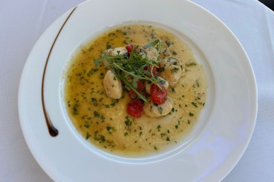 Dessert glacé garni de fraises fraîches, de morceaux de noix et de caramel, présenté sur une assiette blanche.