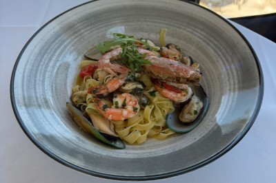 Dessert glacé garni de fraises fraîches, de morceaux de noix et de caramel, présenté sur une assiette blanche.