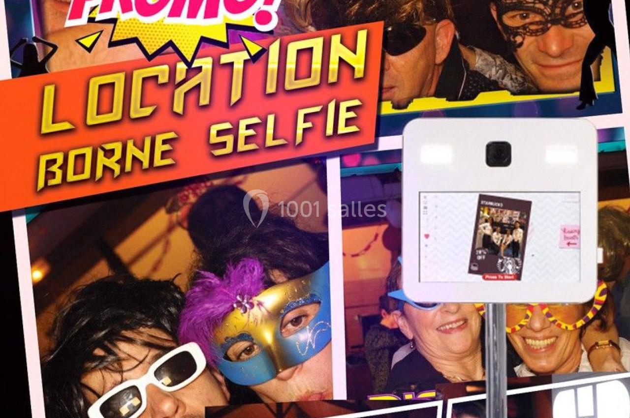 Photo d'une borne selfie entourée de personnes déguisées lors d'un événement festif avec décorations colorées.