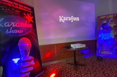 Homme jouant au jeu de la grenouille en bois, avec des palets et une version mobile affichée sur un téléphone.