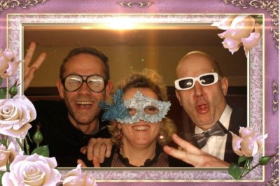 Homme jouant au jeu de la grenouille en bois, avec des palets et une version mobile affichée sur un téléphone.