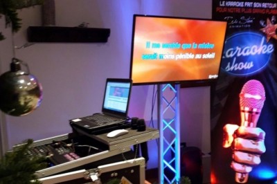 Homme jouant au jeu de la grenouille en bois, avec des palets et une version mobile affichée sur un téléphone.