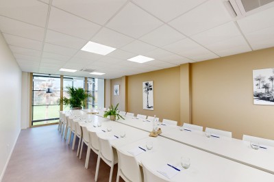 Vue aérienne d'un espace vert avec un bâtiment moderne, des arbres, des toiles d'ombrage et des champs en arrière-plan.