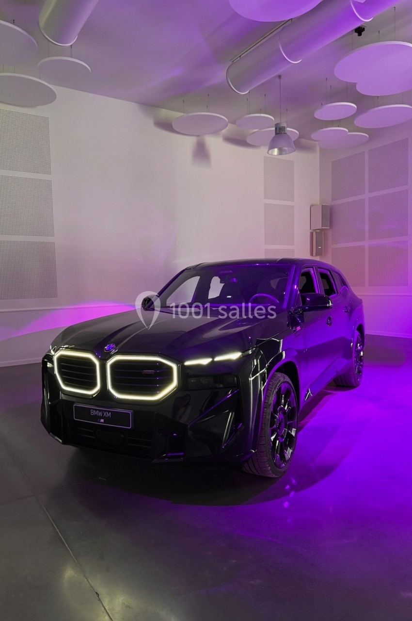 SUV noir exposé dans une salle moderne, éclairé par des lumières violettes et blanches, avec un design avant lumineux.