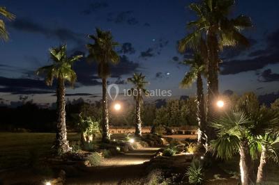 Groupe de personnes rassemblées sur une terrasse et une pelouse, entourées de végétation sous un ciel dégagé.