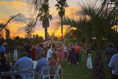 Groupe de personnes rassemblées sur une terrasse et une pelouse, entourées de végétation sous un ciel dégagé.