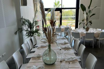Groupe de personnes rassemblées sur une terrasse et une pelouse, entourées de végétation sous un ciel dégagé.