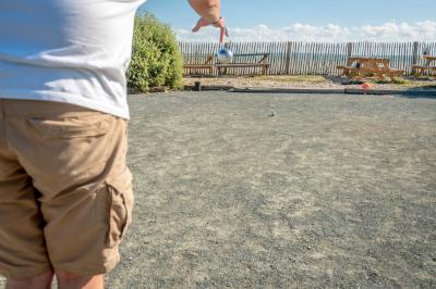 Groupe de personnes rassemblées autour de tables de pique-nique dans un espace extérieur avec des arbres et des parasols.